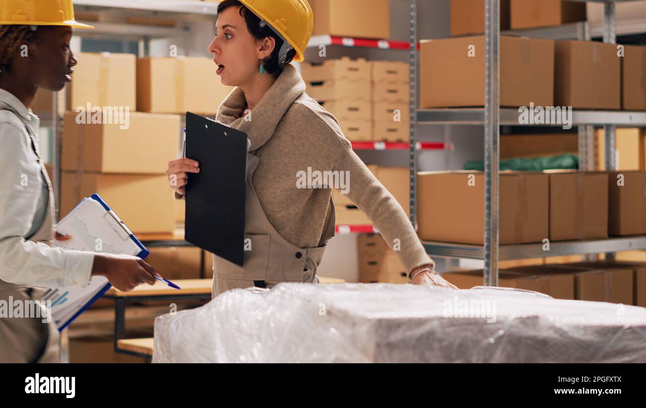 Two women analyzing list of products in warehouse to work on stock