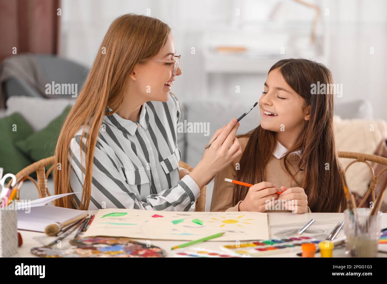 Drawing teacher giving private art lesson to little girl at home Stock