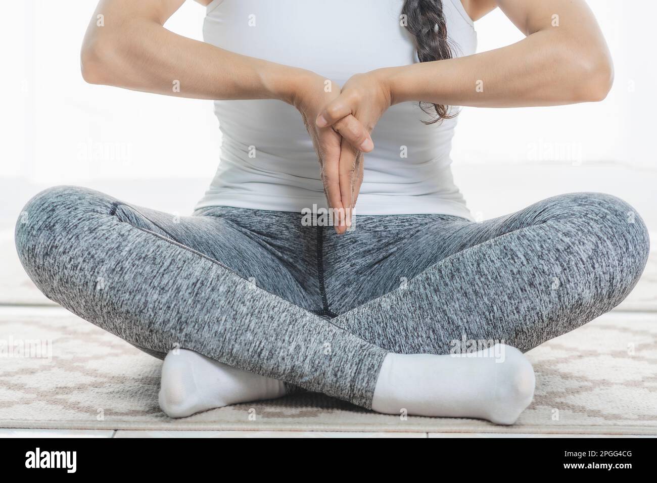 Woman does Yoga indoors, close-up, does deep meditation postures. It is very quiet. Stock Photo