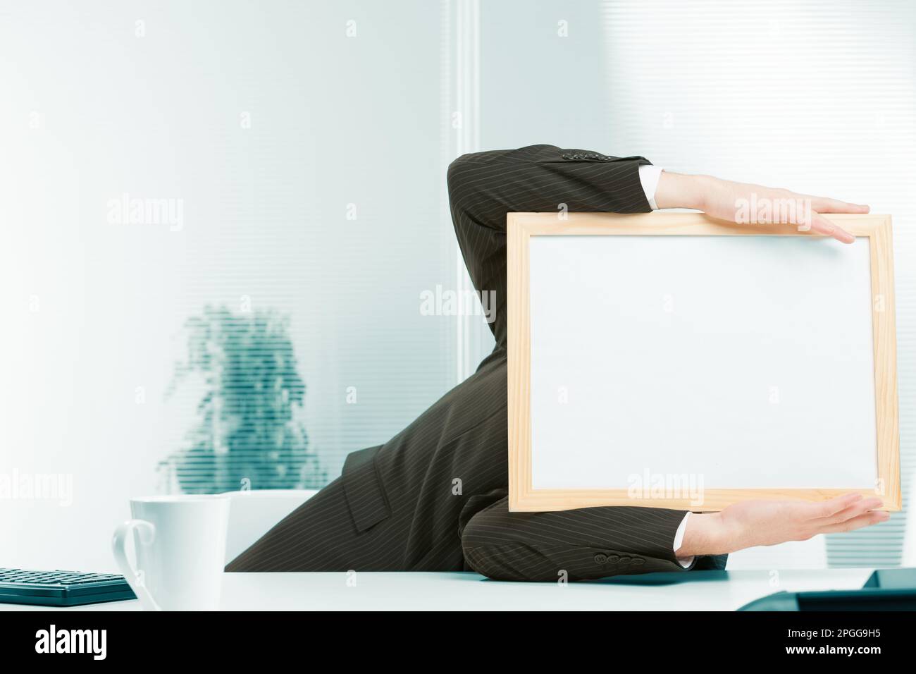 Office workplace, a sign-headed man framed in light-colored wood leans to the side from a fainting spell, a shock from strong negative news. He holds Stock Photo