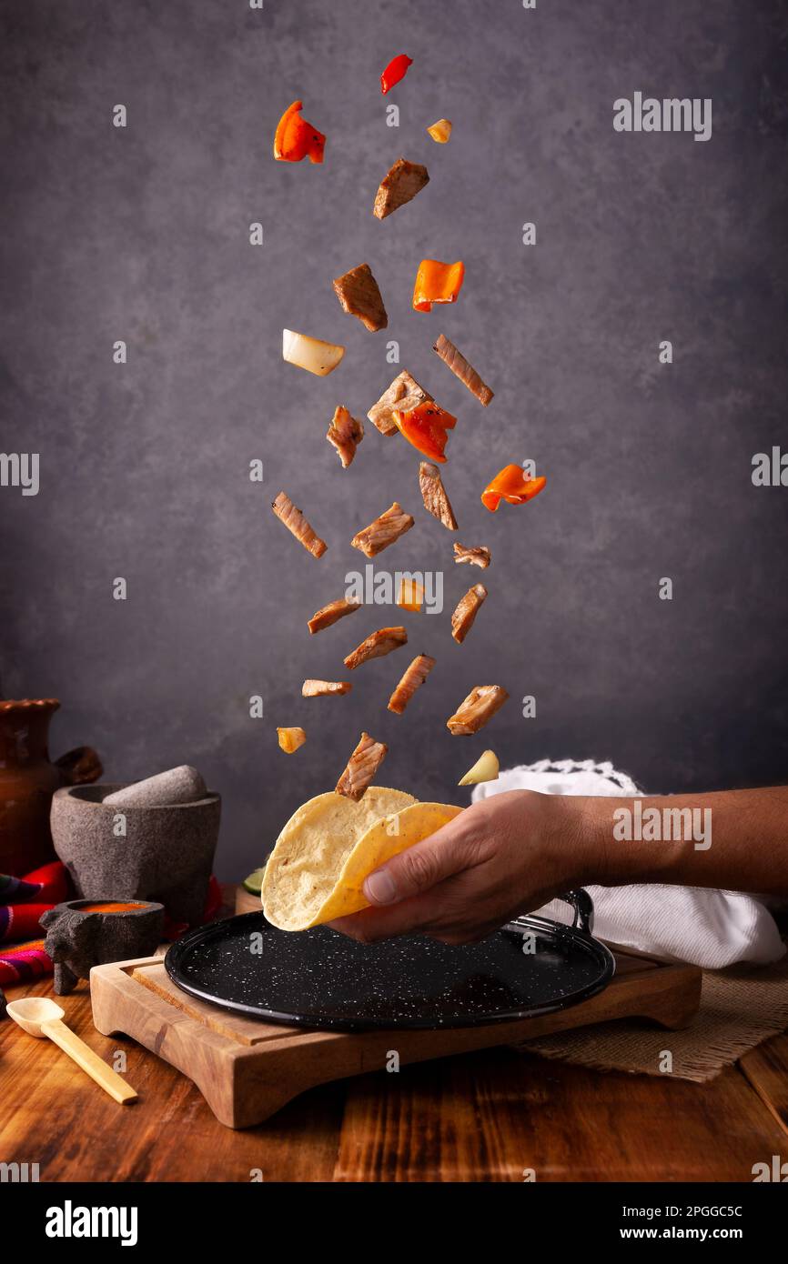 Exploding Beef Fajita Taco ingredients falling on human hand with corn ...