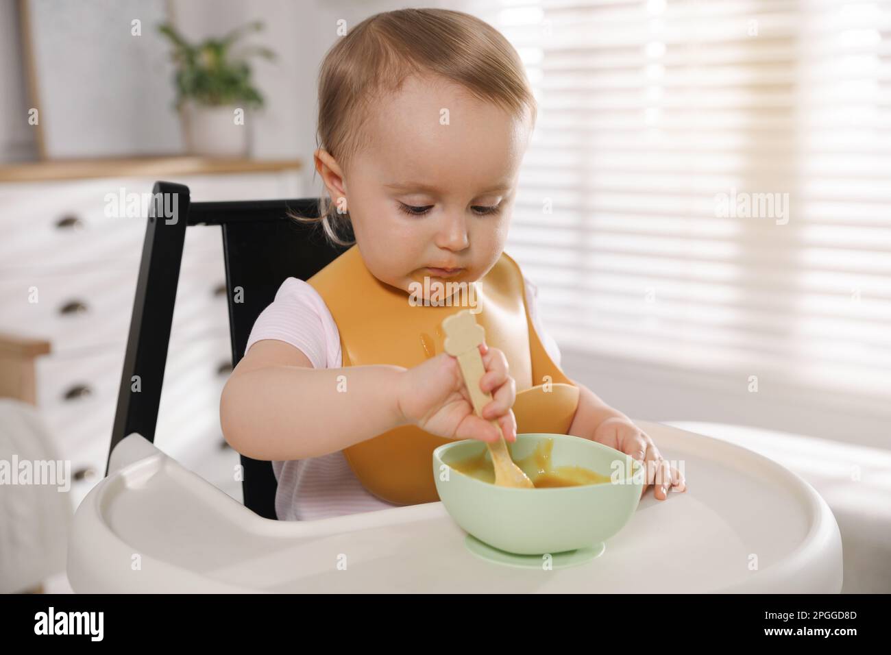 Cute little baby wearing bib while eating at home Stock Photo Alamy