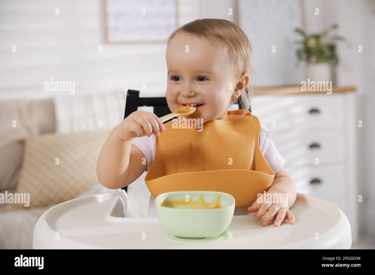 Cute little baby wearing bib while eating at home Stock Photo Alamy