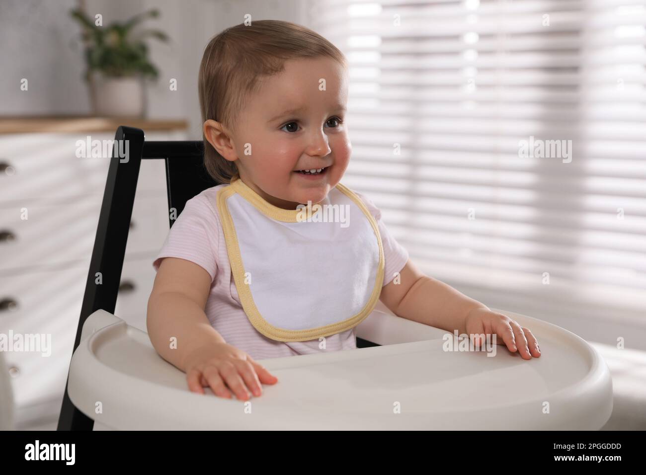 Cute little baby wearing bib in highchair at home Stock Photo Alamy