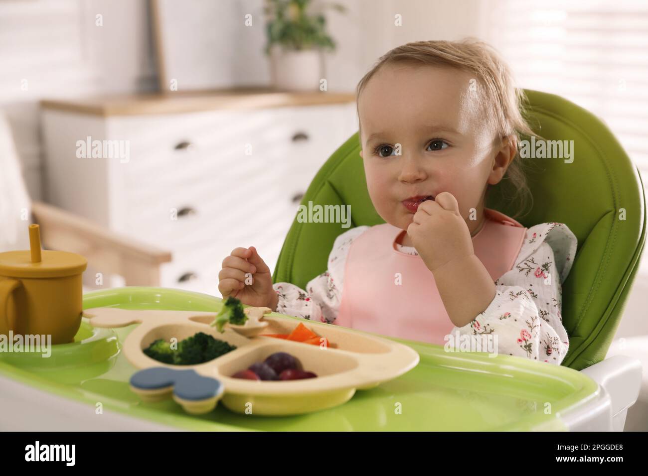 Cute little baby wearing bib while eating at home Stock Photo - Alamy