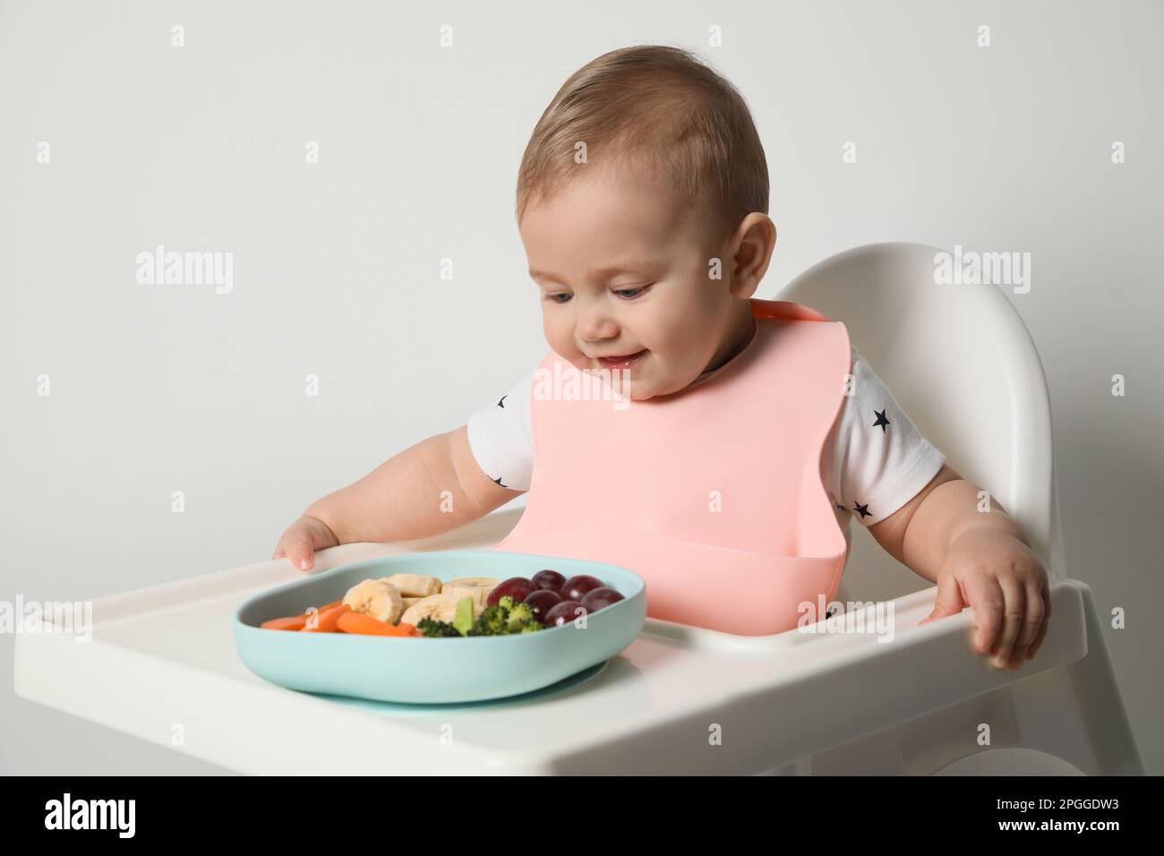 Cute little baby wearing bib while eating on white background Stock ...