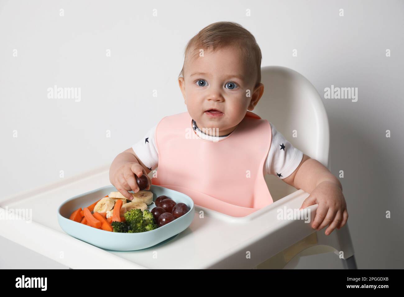 Cute little baby wearing bib while eating on white background Stock ...