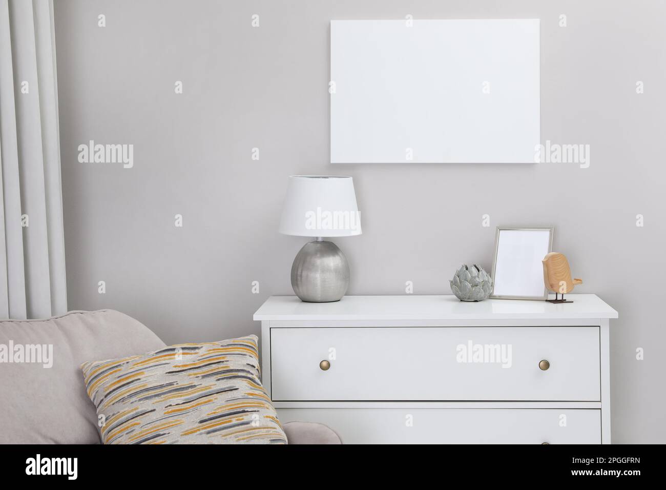 Blank canvas on wall over chest of drawers with decor in room. Space