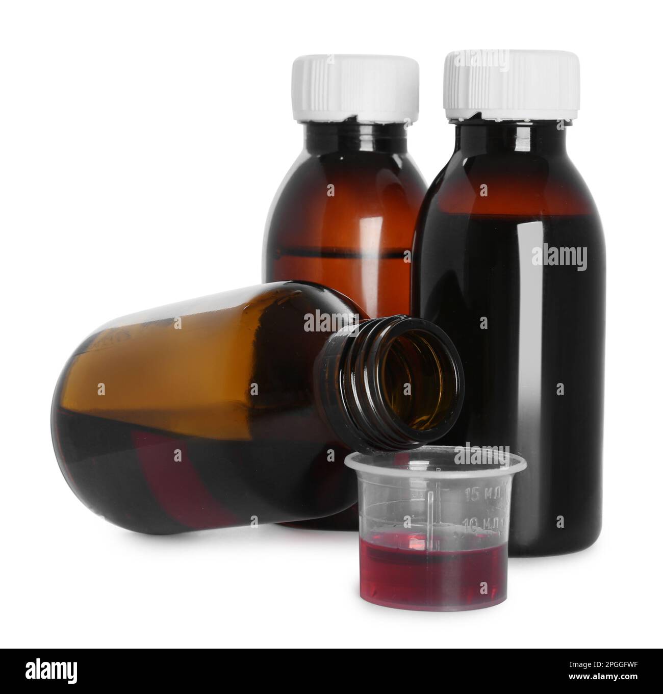 Bottles of cough syrup and measuring cup on white background Stock