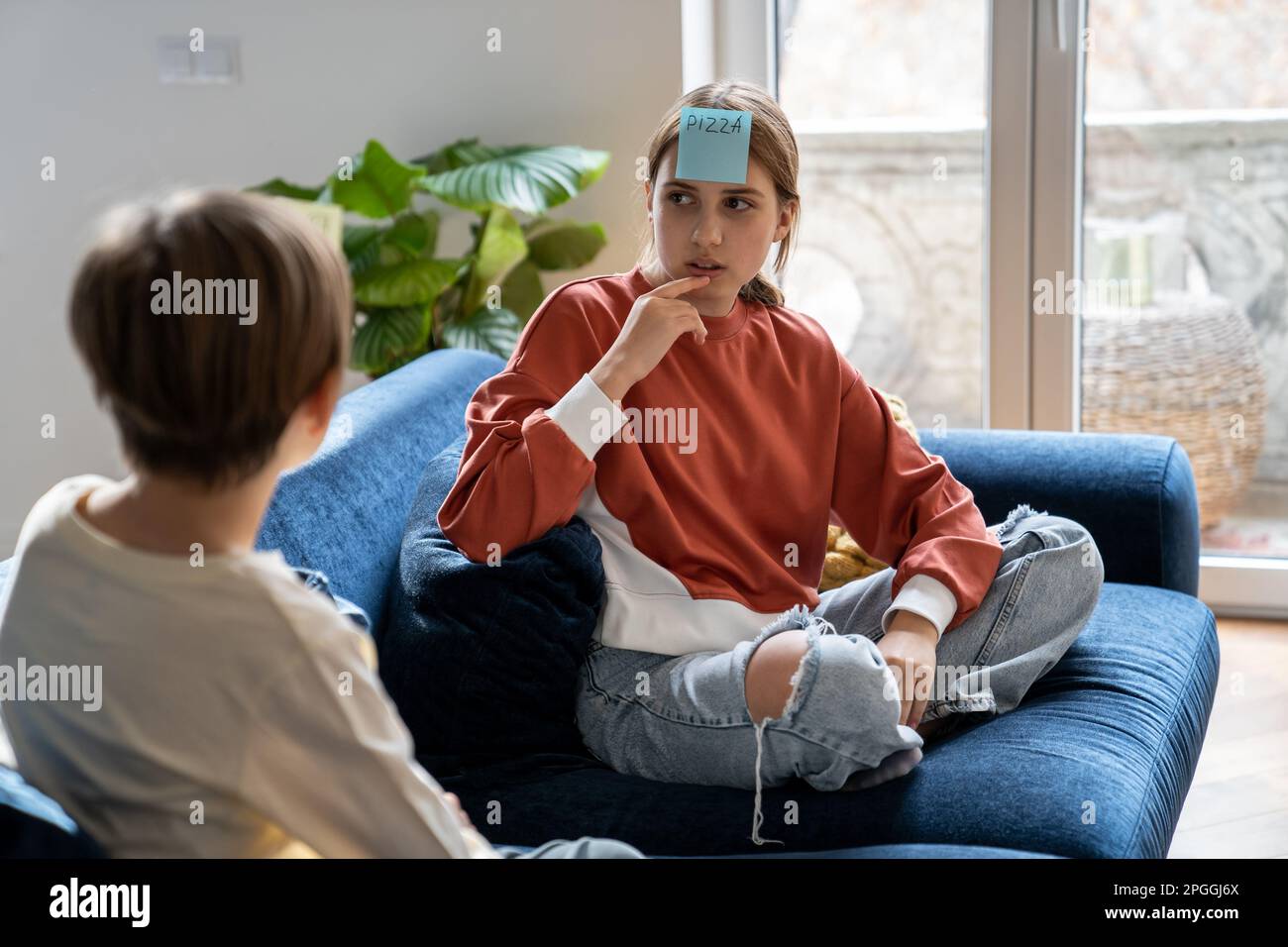 Pensive teenage girl pondering guess word on sticker on forehead