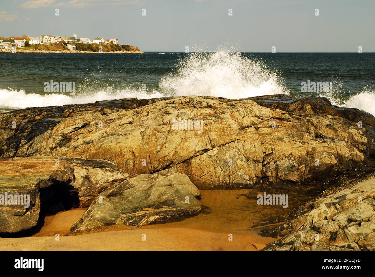 Large ocean waves crash against the rocky coast on a summer day at the