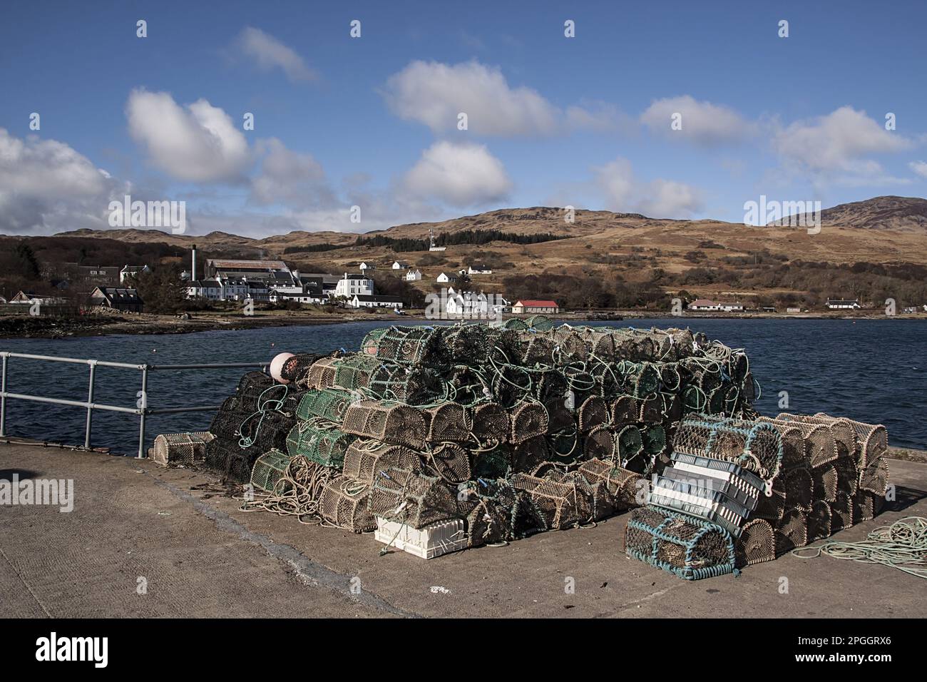 Lobster pots on the Jura Pier with Jura Hotel and whisky distillery behind it Stock Photo