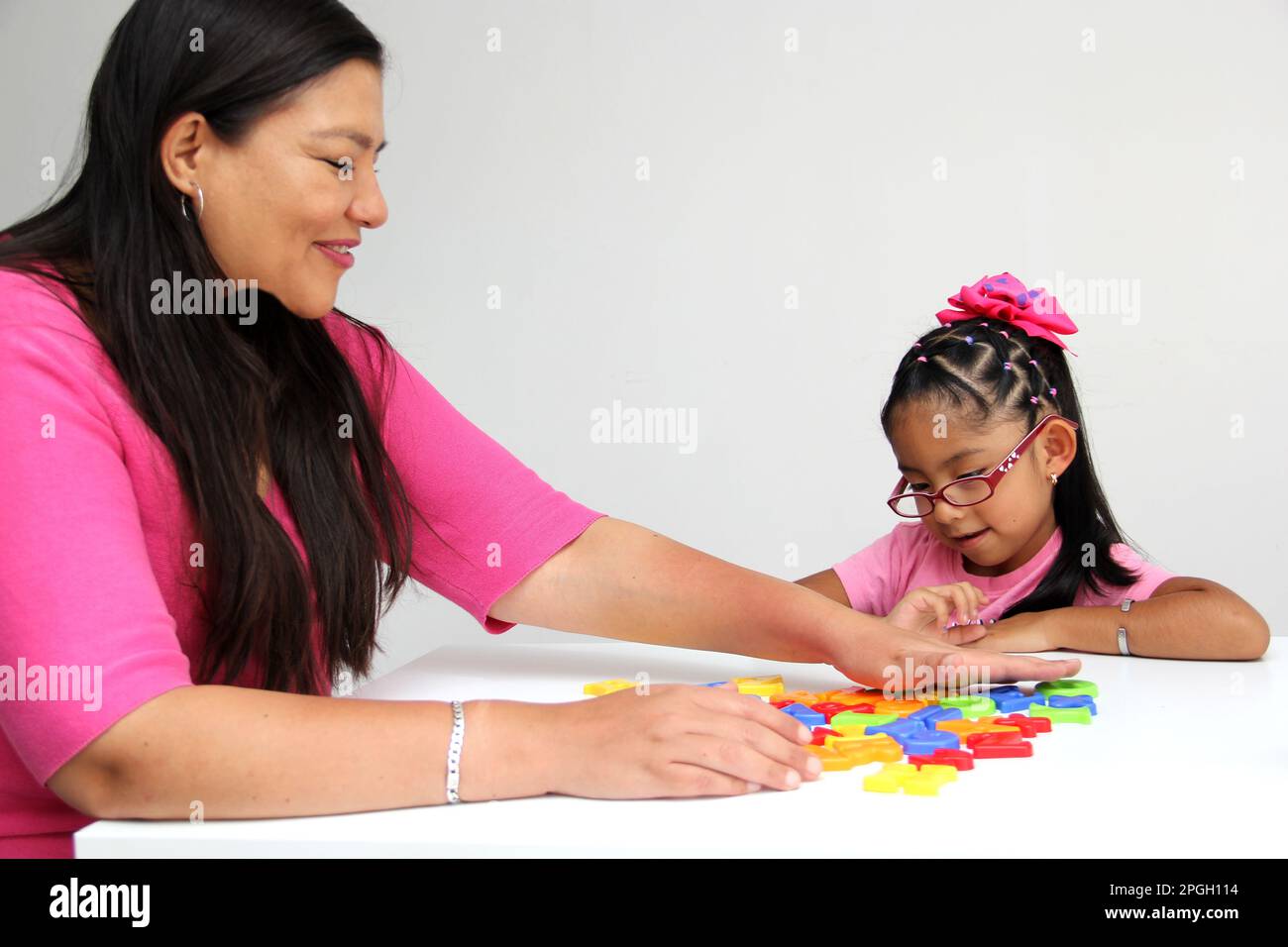 4-year-old Latina girl takes child therapy with the psychotherapist through games to treat her atuism and reflects emotions to learn Stock Photo