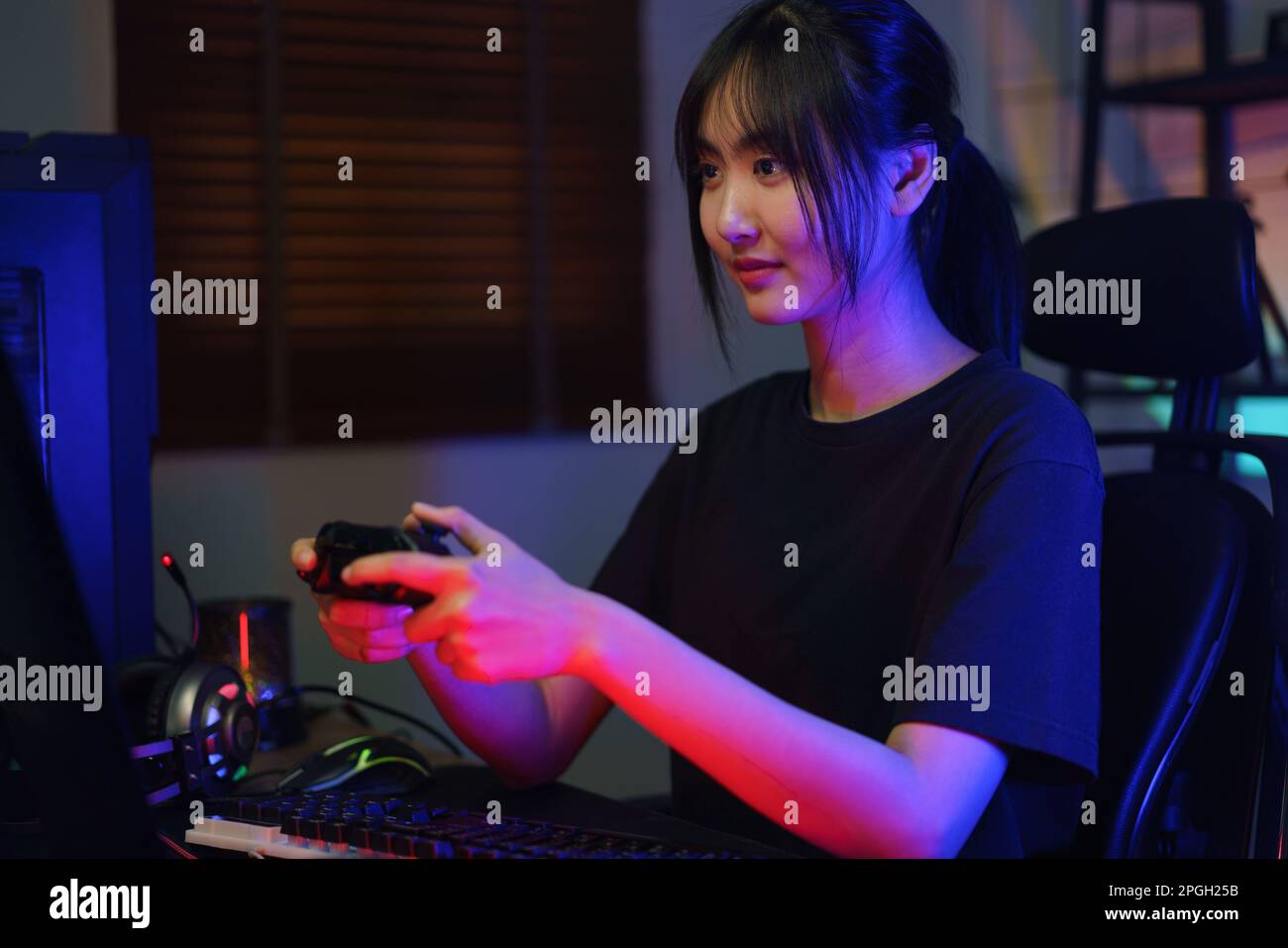 Female cyber hacker gamer using controller joystick to playing or streaming games on computer. Stock Photo