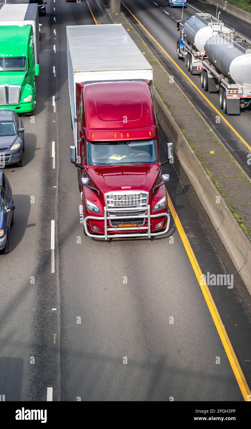 Industrial long hauler big rig burgundy semi truck tractor with extended cab for truck driver rest transporting cargo in dry van semi trailer driving Stock Photo