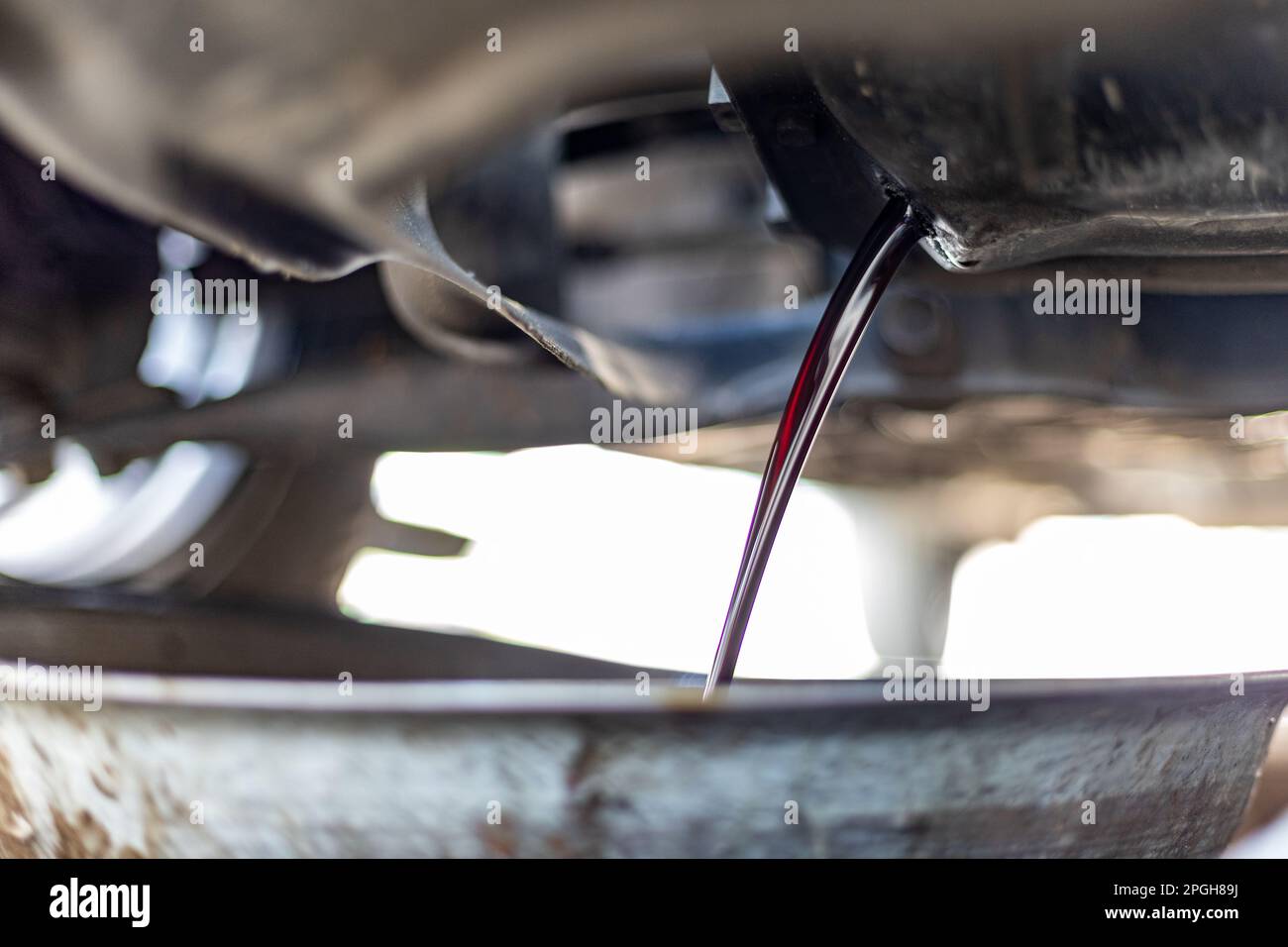 Changing engine dirty oil being drained from underneath a car into a