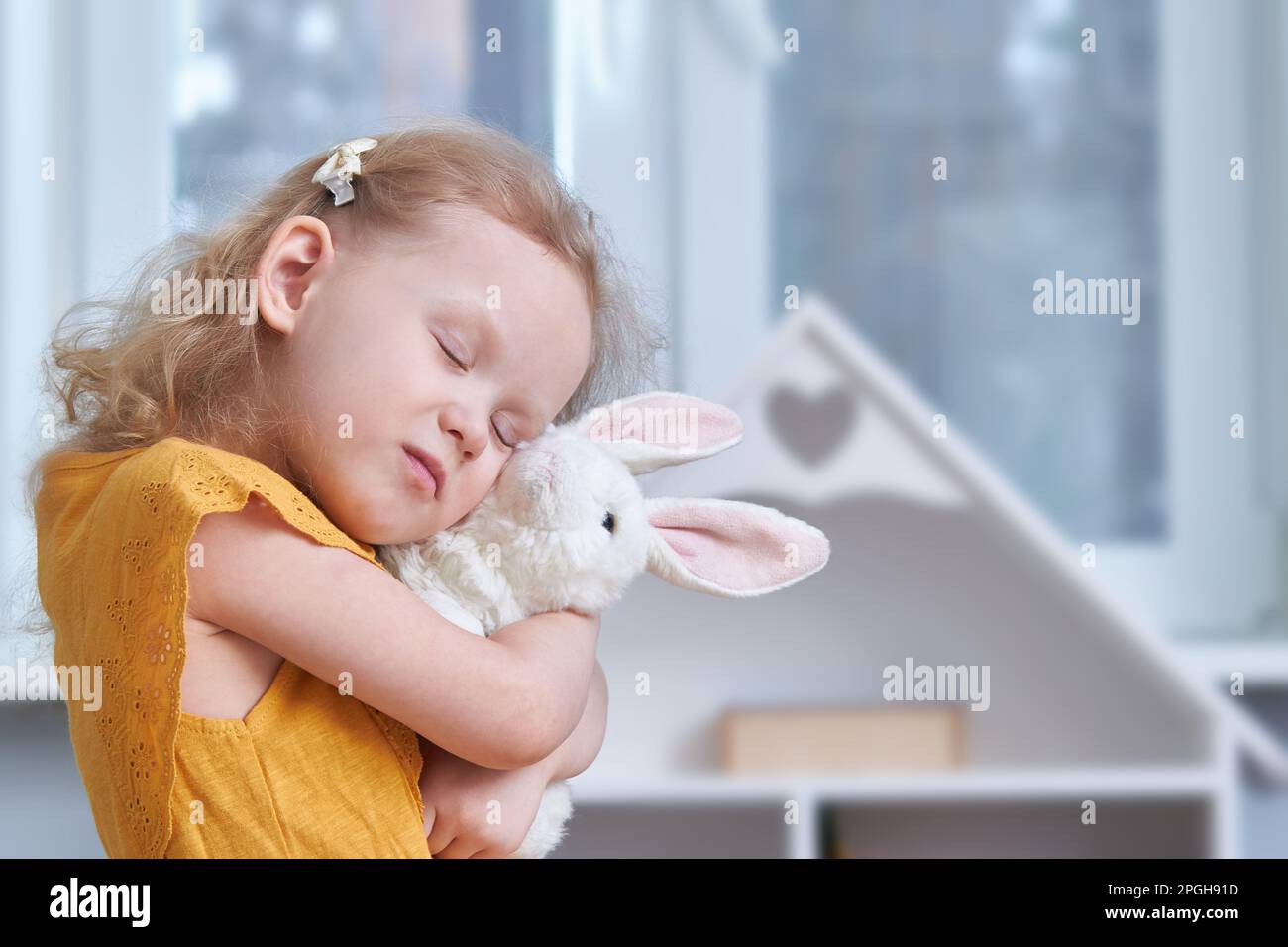A girl hugs a white rabbit toy. Close-up. The concept of reconciliation and love Stock Photo