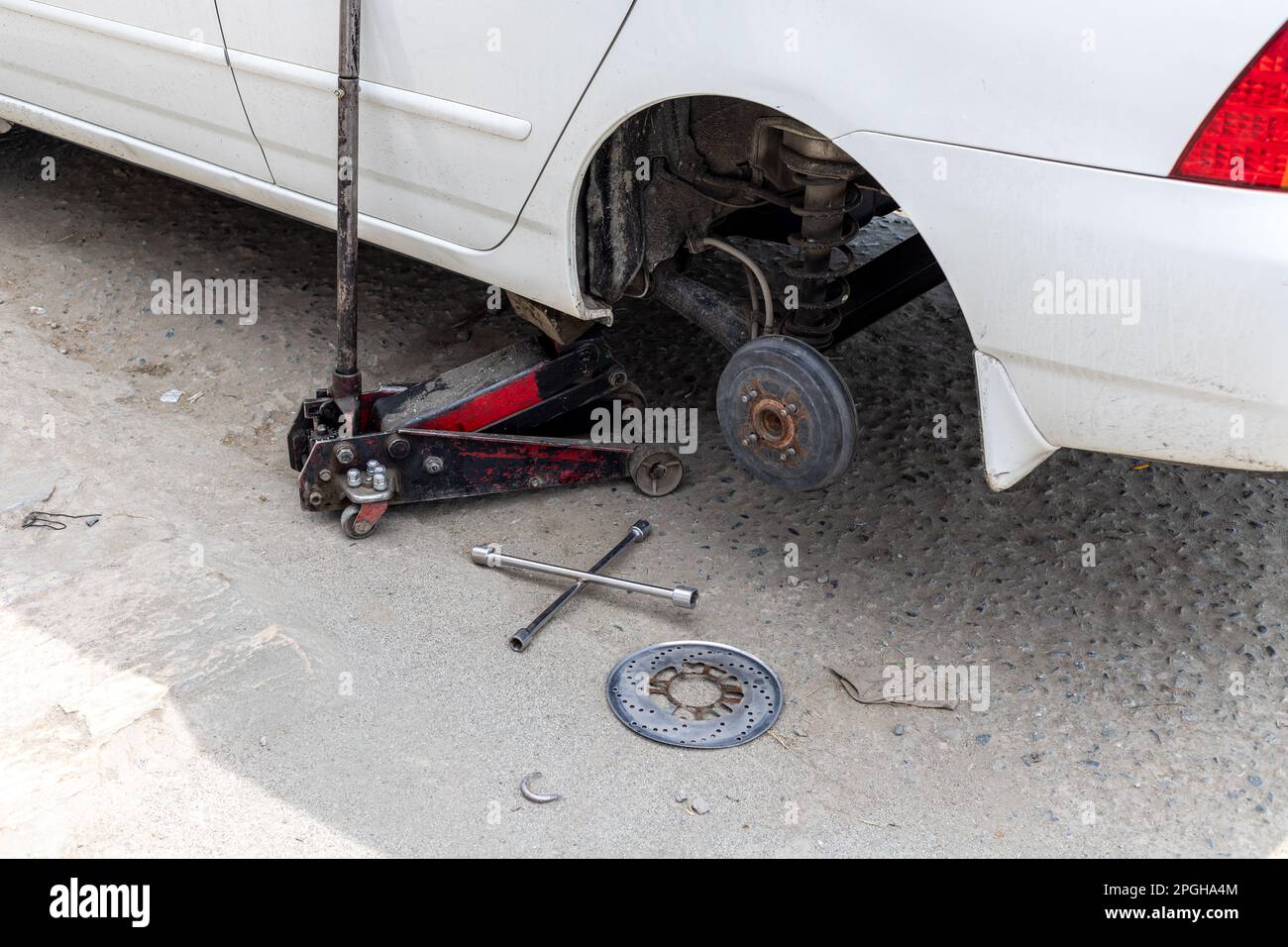 Changing car rear wheel lifted by hydraulic jack Stock Photo