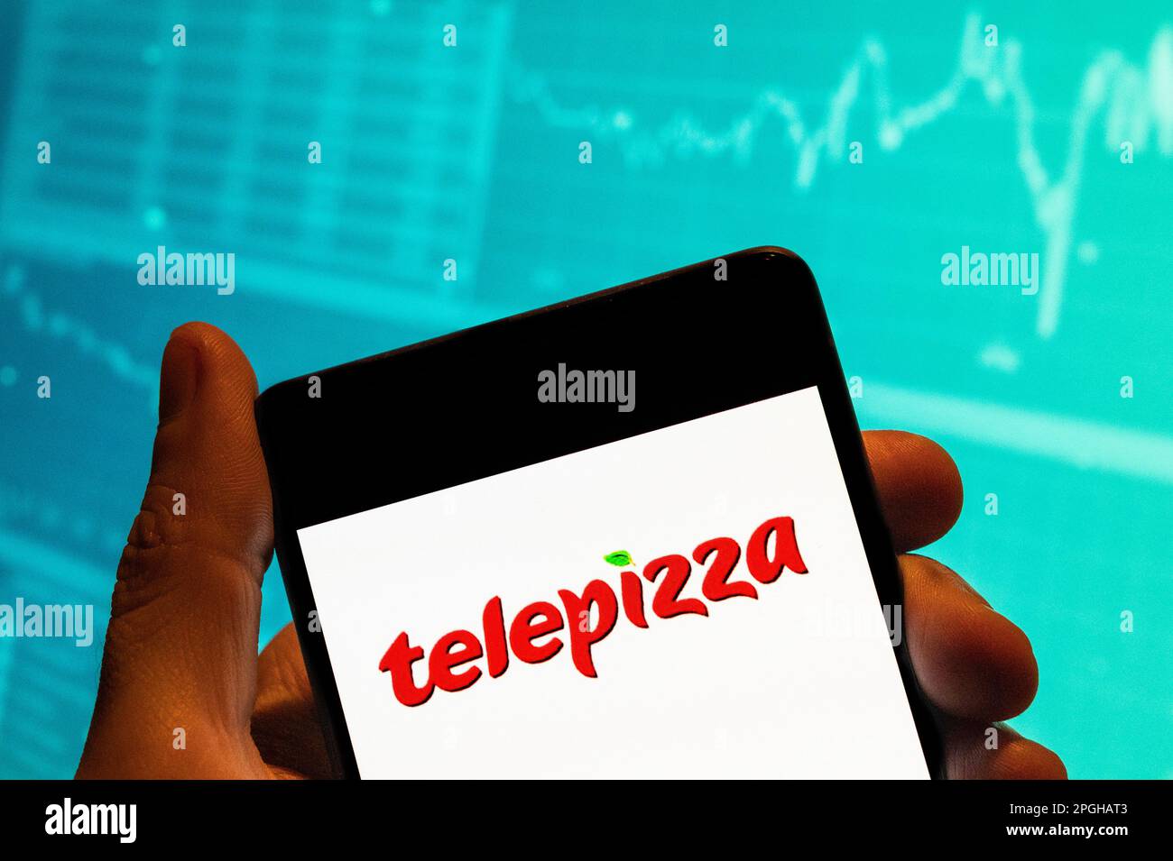 In this photo illustration, the Spanish pizza restaurant franchise Telepizza logo seen displayed on a smartphone with an economic stock exchange index graph in the background. Stock Photo