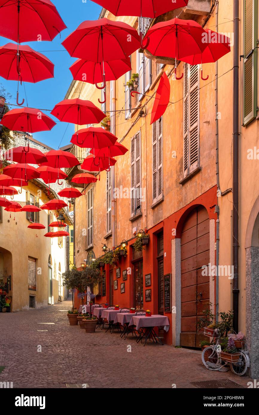 Luino, Italy - 16 March, 2023: vertical view of a cobblestone street with small shops and colorful decorations in the old city center of Luino Stock Photo