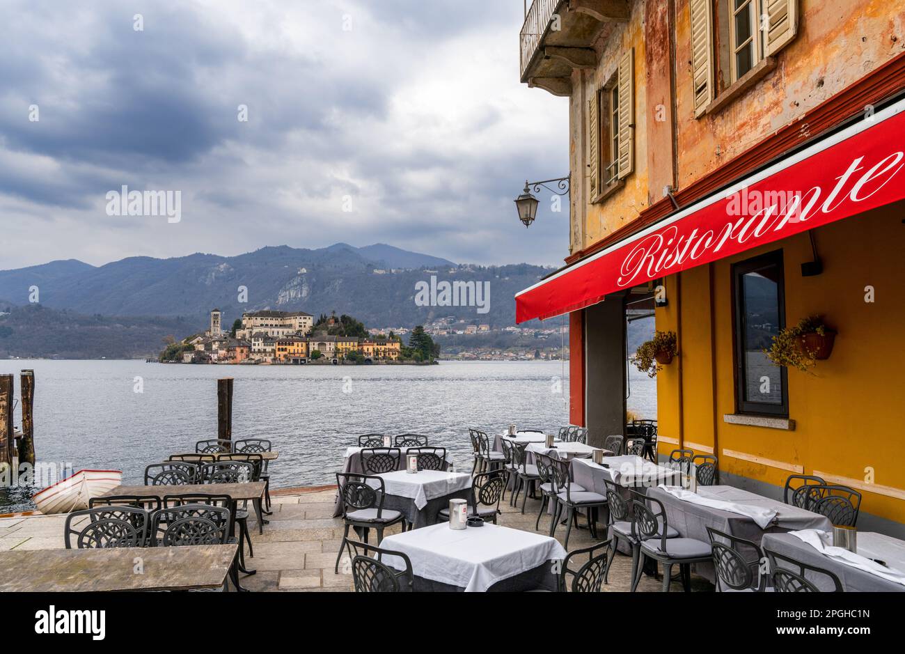 Orta San Giulio, Italy - 13 March, 2023: lakeside restaurant and Orta Island in Lake Orta in the Italian Lake District Stock Photo