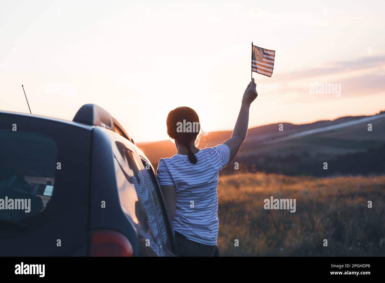 Woman holding an American flag on a road trip. Independence Day or traveling in America concept. Stock Photo
