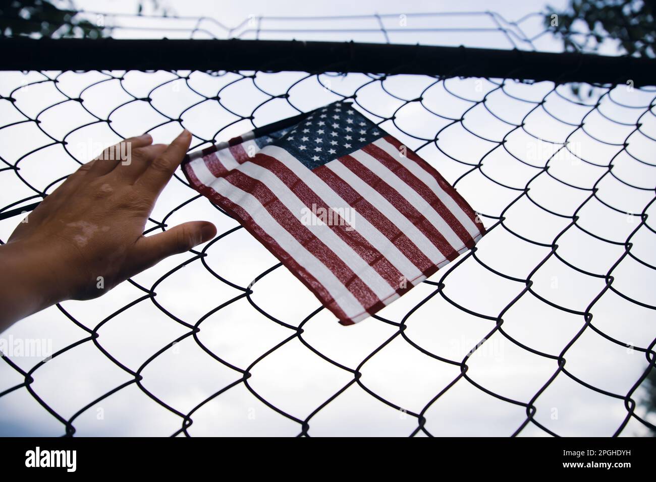 Close up of a American Flag in hand attached to a chain link fence. American  immigration and United States refugee crisis concept Stock Photo - Alamy