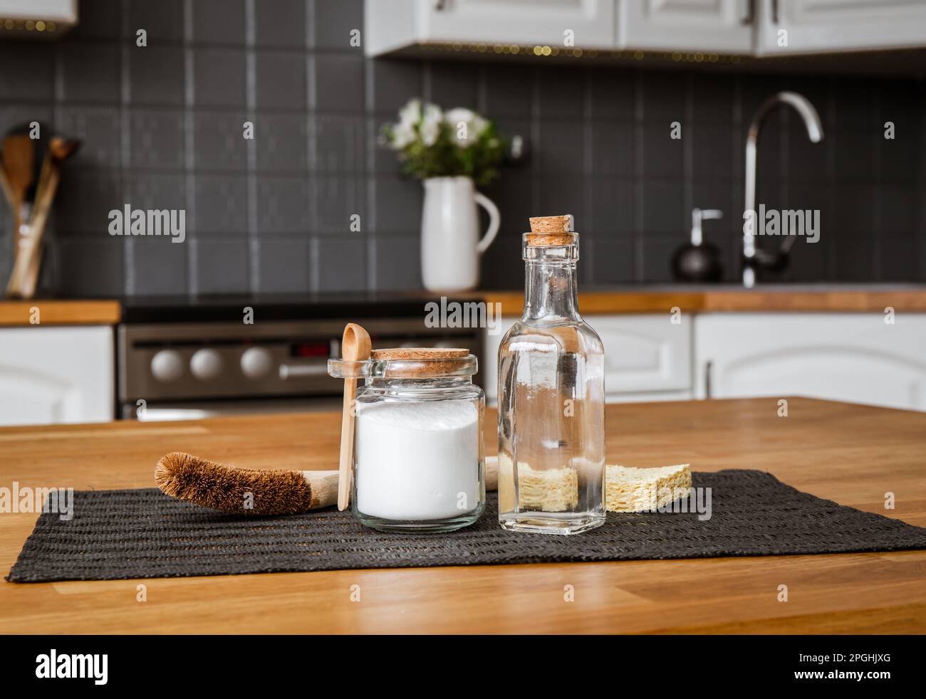 Using baking soda Sodium bicarbonate and white vinegar for home kitchen cleaning concept. White vinegar in glass bottle and baking soda in glass jar. Stock Photo