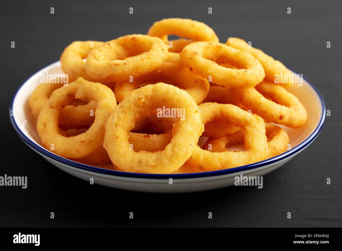 Homemade Breaded Onion Rings on a Plate on a black surface, side view