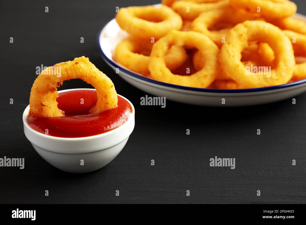 Homemade Breaded Onion Rings with Ketchup on a Plate on a black