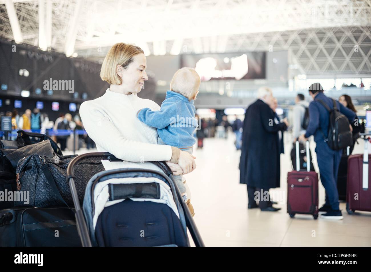 Motherat travelling with his infant baby boy child, walking, pushing