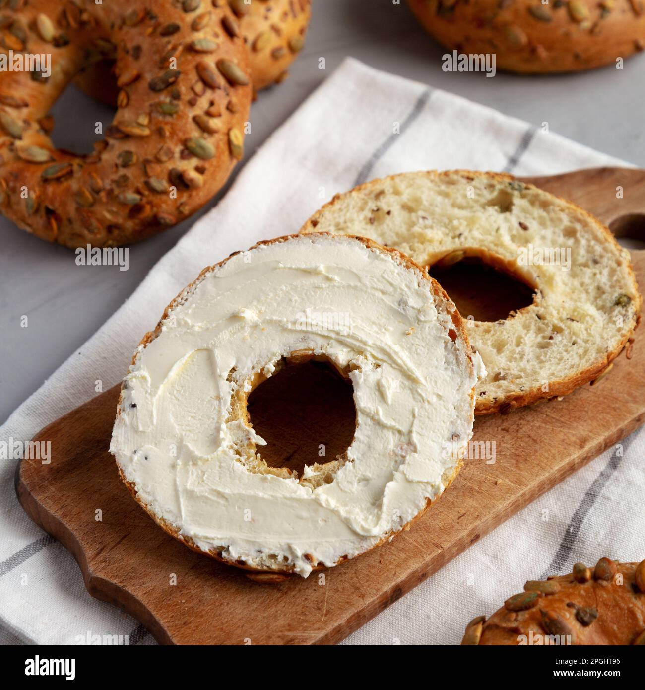 Homemade Whole Grain Bagel with Cream Cheese on a rustic wooden board, side view. Stock Photo