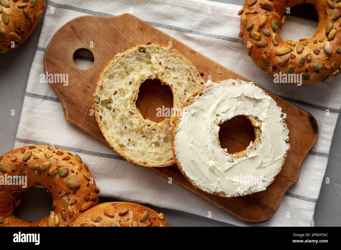 Homemade Whole Grain Bagel with Cream Cheese on a rustic wooden board, top view. Stock Photo