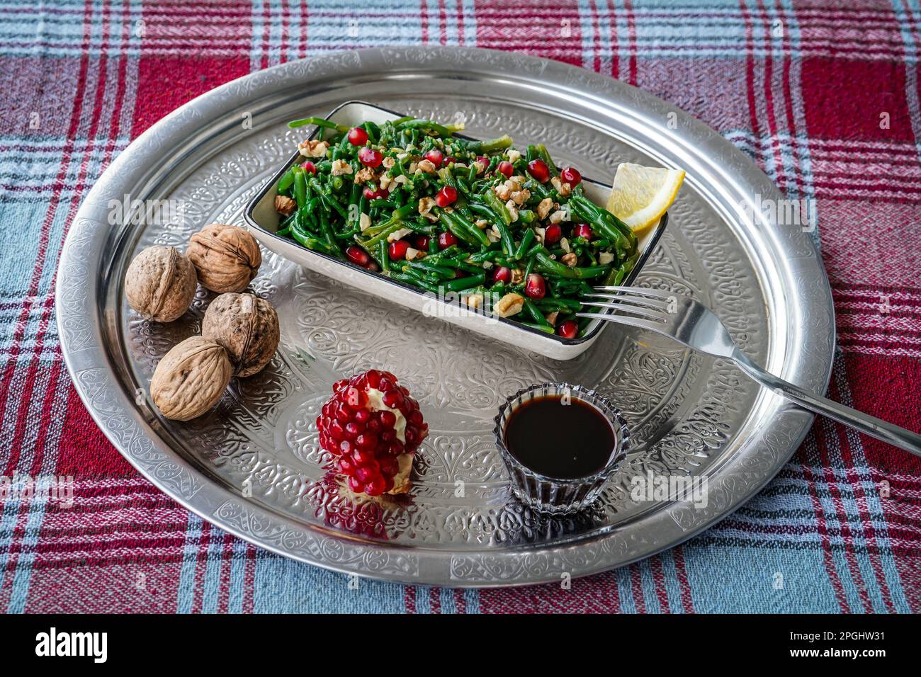 Samphire salad with walnut, pomegranate, lemon, and pomegranate syrup (dib roman) made by traditional anatolian style on turkish tray and tablecloth Stock Photo