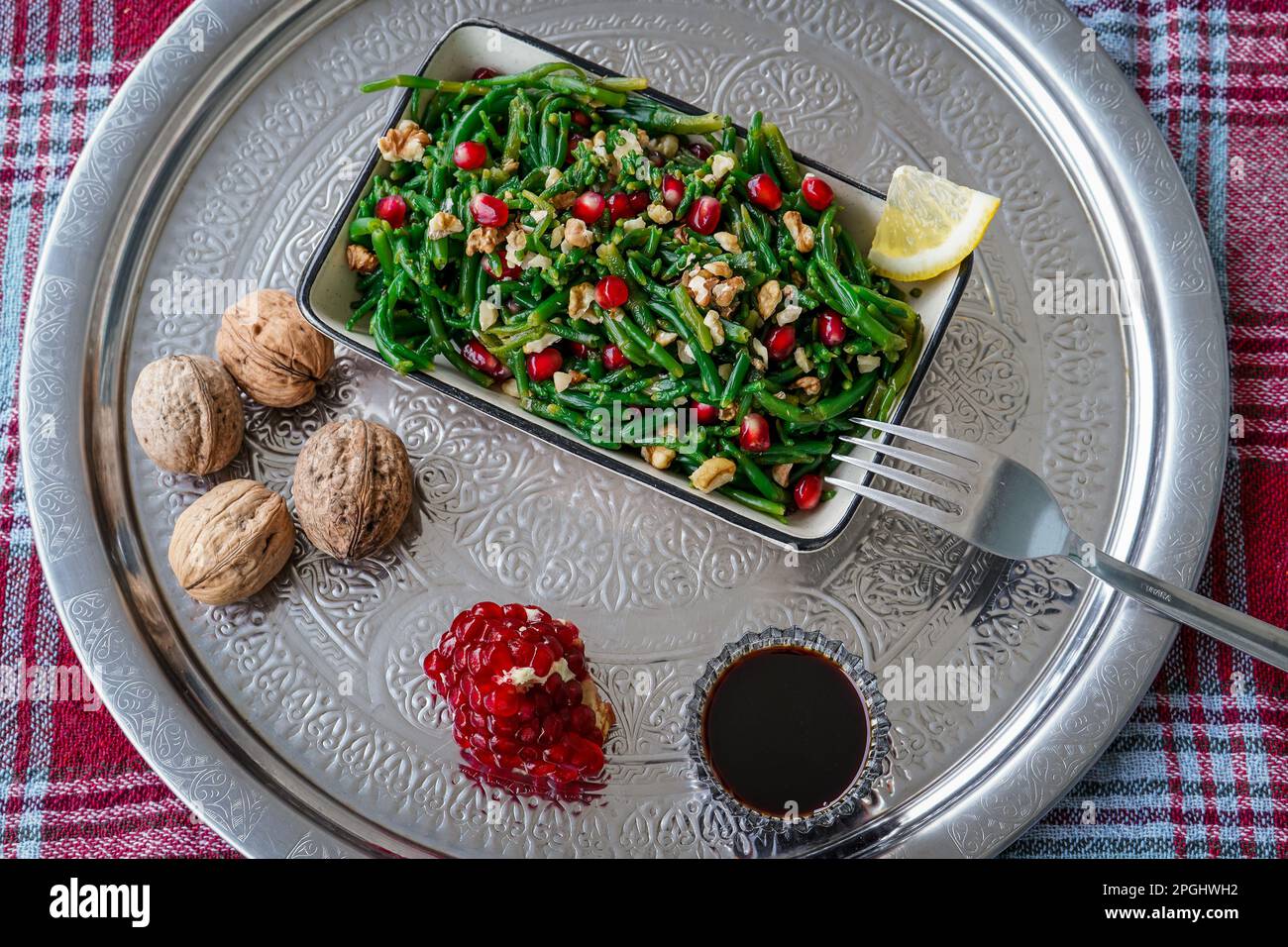Samphire salad with walnut, pomegranate, lemon, and pomegranate syrup (dib roman) made by traditional anatolian style on turkish tray and tablecloth Stock Photo