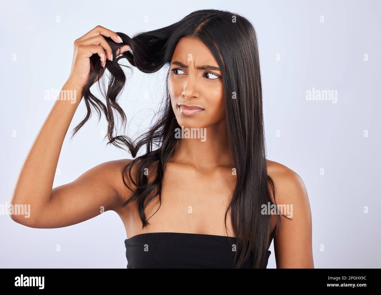 Indian woman, problem or bad hair care in studio for unhealthy damage, trouble or frizzy texture. Sad, upset or frustrated young girl model in self Stock Photo