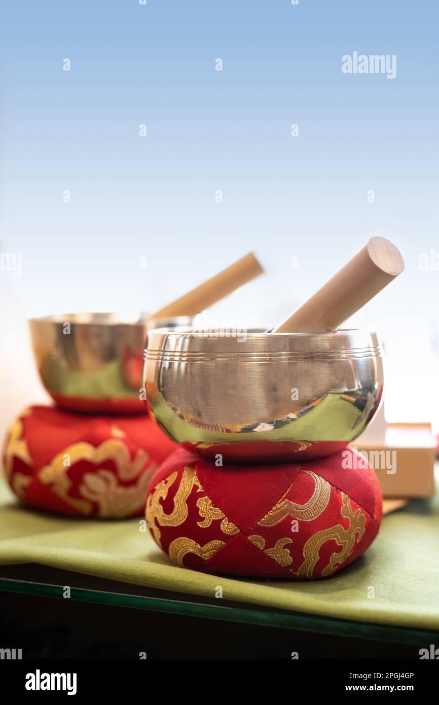 Two singing bowls or standing bells on red cushions with golden embroidery, used for music, meditation and relaxation or for personal spirituality, co Stock Photo