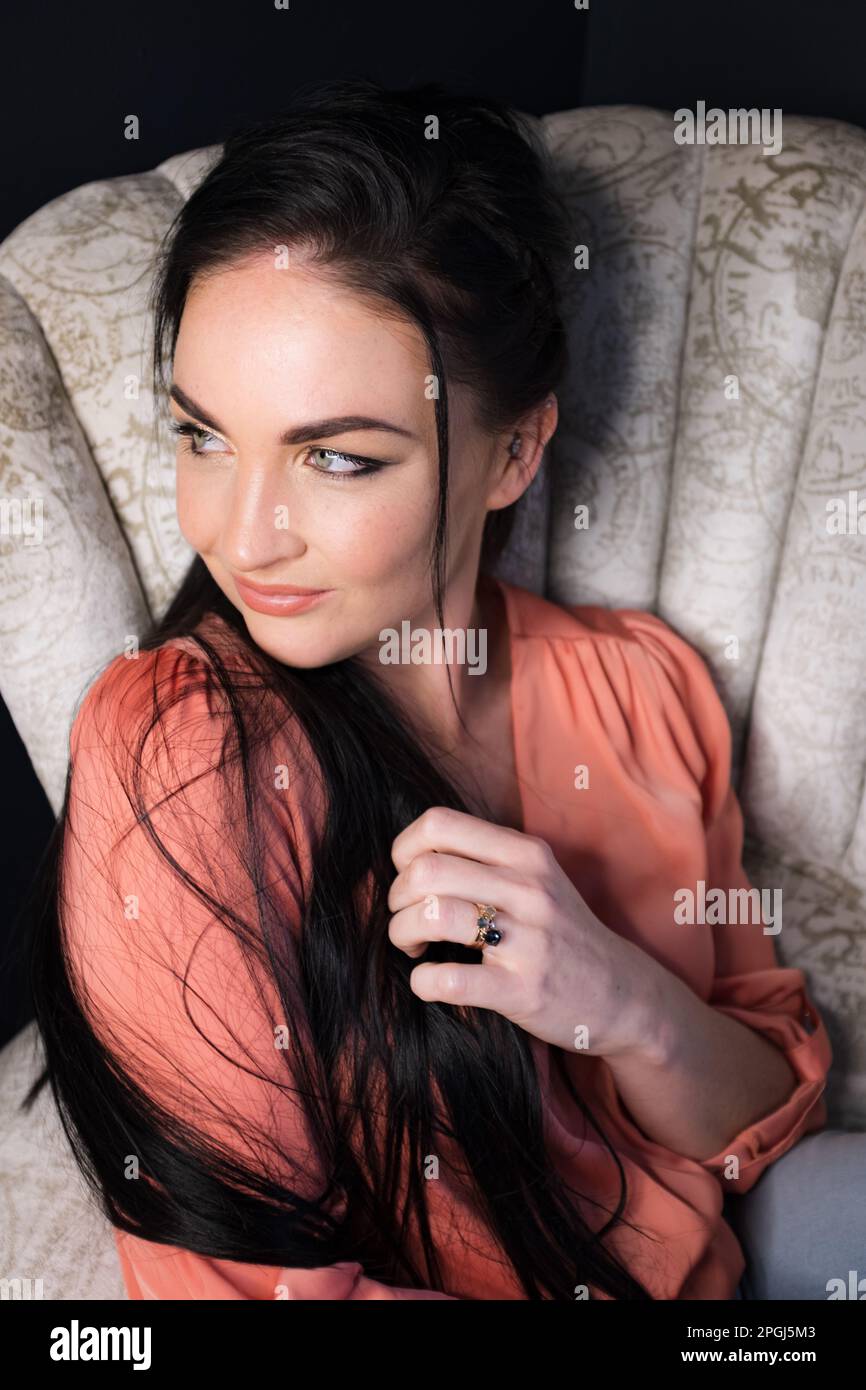 A dark-haired brunette on a Vintage White Chair Stock Photo
