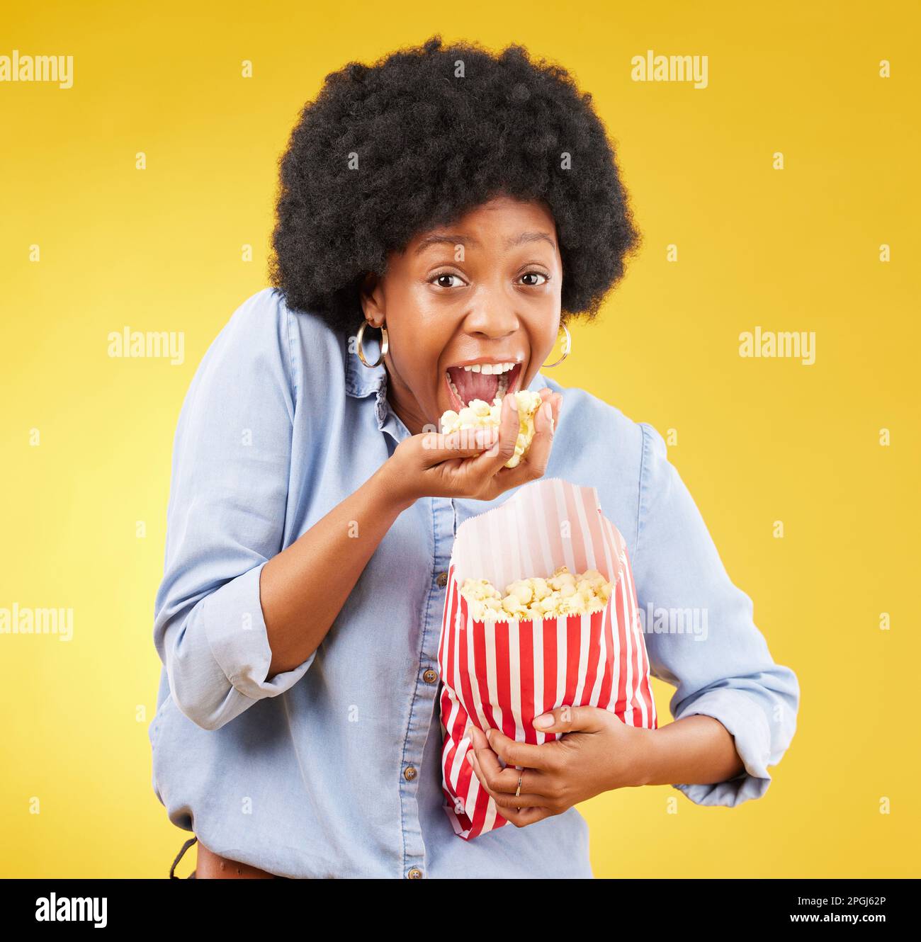 Happy, food and popcorn with black woman in studio for movie, streaming service and cinema. Crazy, comedy and theatre with female and snack isolated Stock Photo