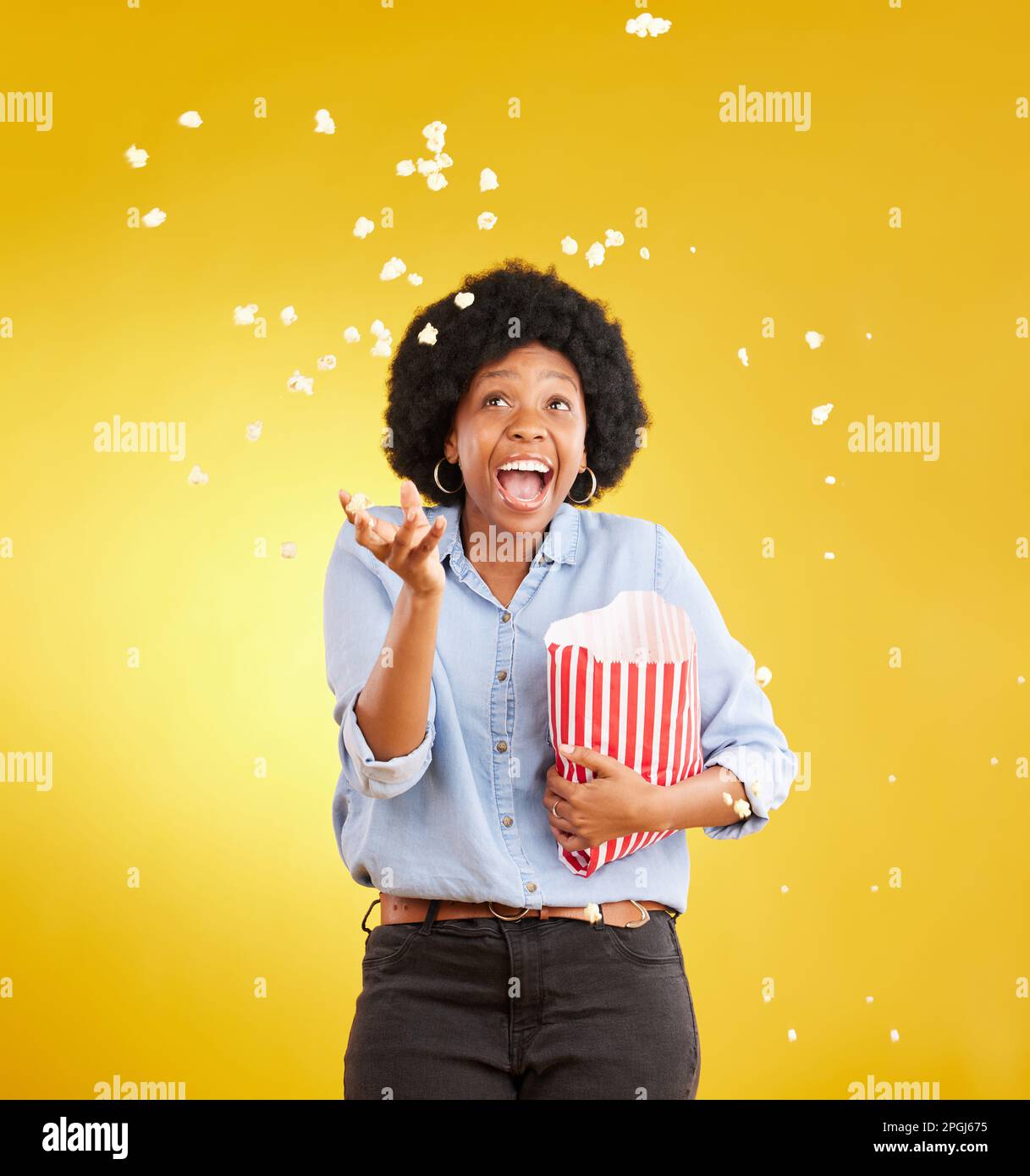 Happy, throwing and popcorn with black woman in studio for movie, streaming service and cinema. Laugh, funny and theatre with female and snack Stock Photo