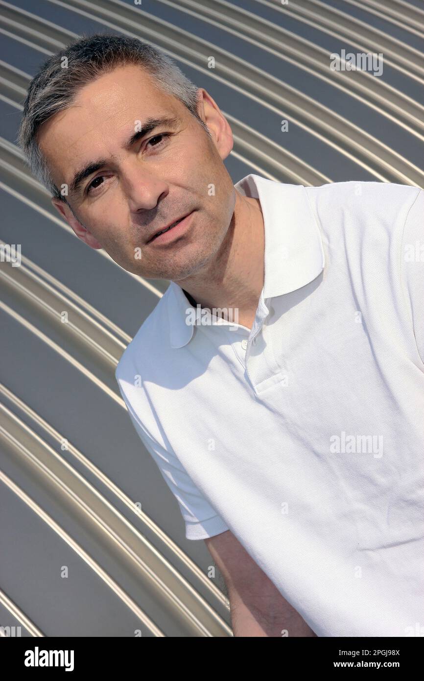 older man in a polo shirt in front of a sheet metal wall, portrait ...