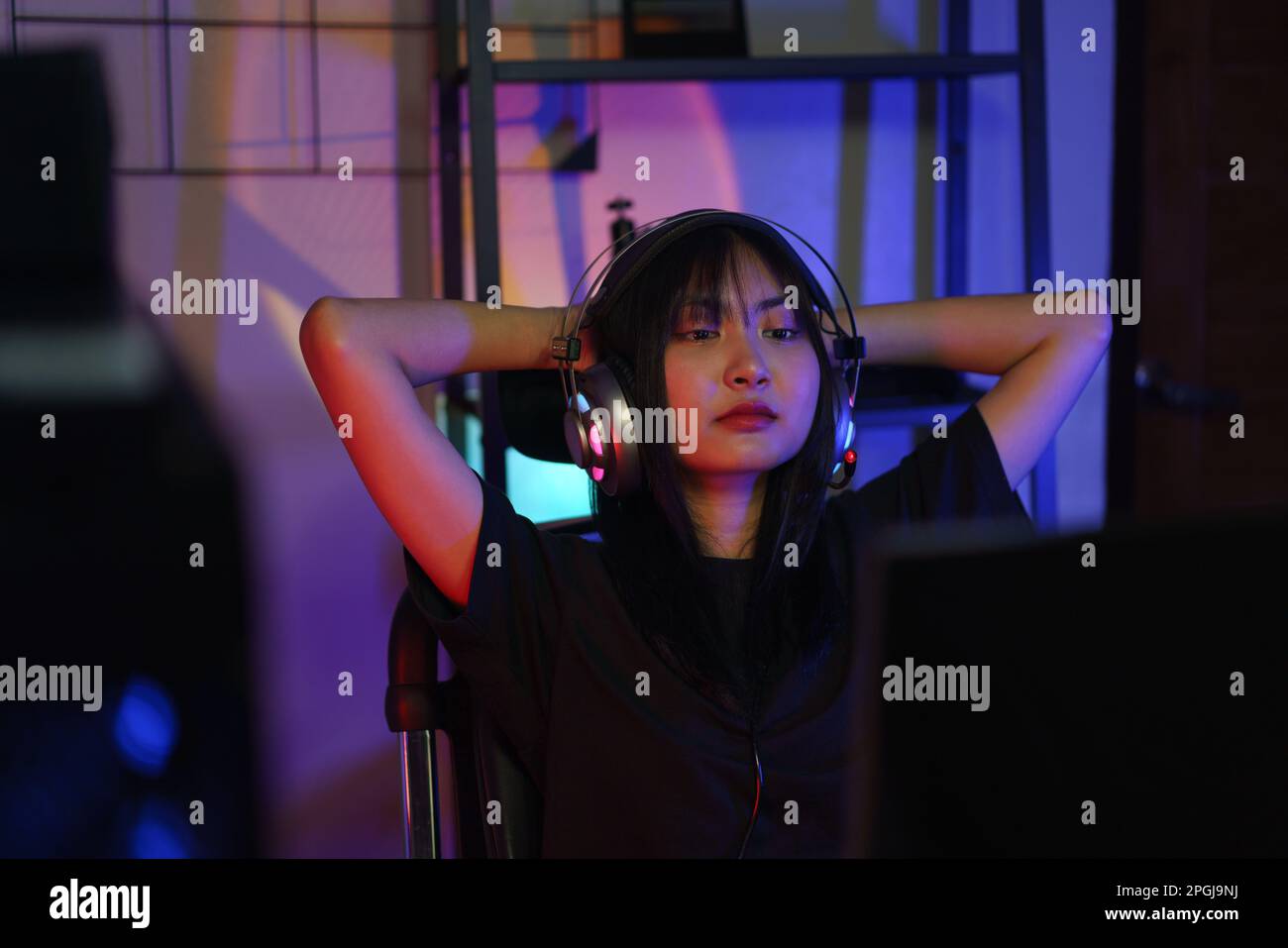 Female cyber hacker gamer holds hands behind head to resting after ...