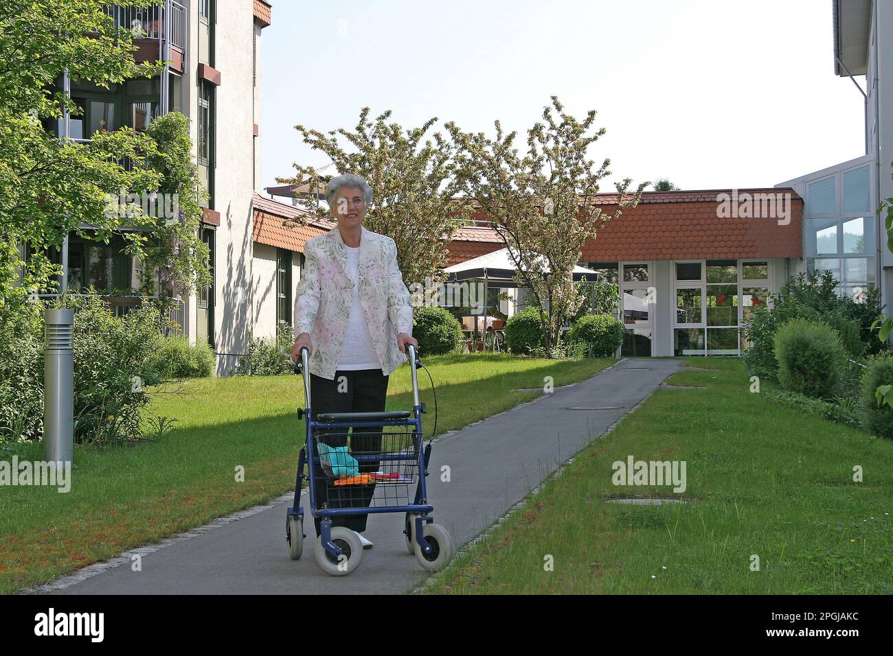 senior woman walking with a rollator in the outdoor area of the senior ...