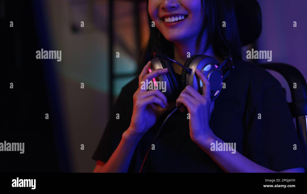 Female cyber hacker gamer in headphone around neck watching video games