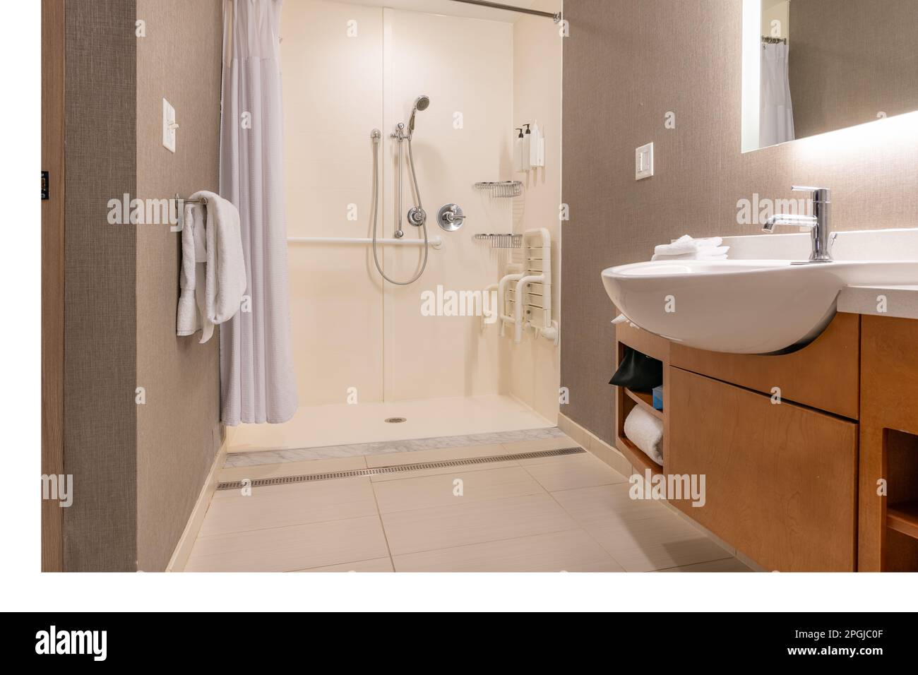Wheelchair accessible hotel bathroom shower with tile floor and walls