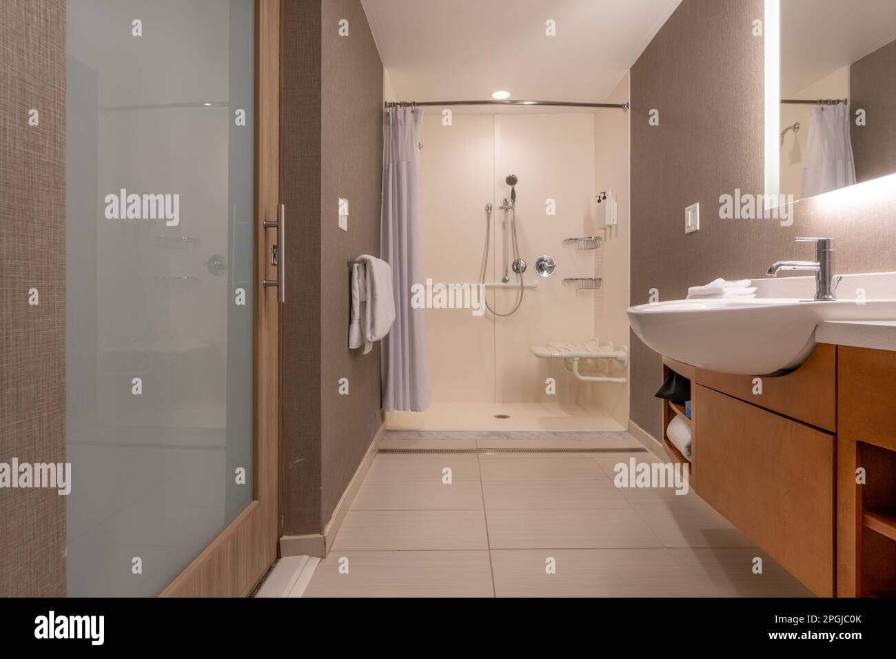 Wheelchair accessible hotel bathroom shower with tile floor and walls. Stock Photo