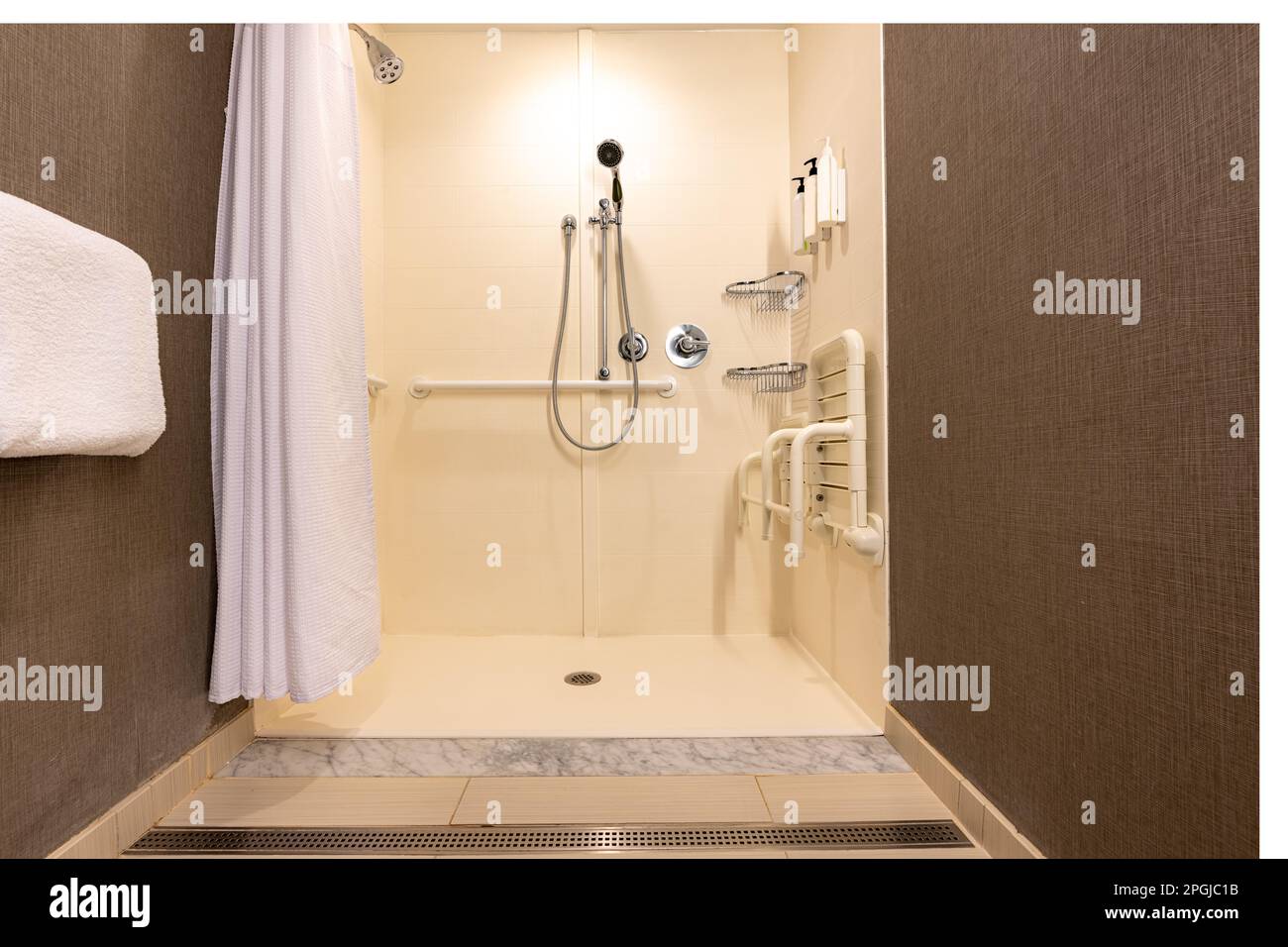Wheelchair accessible hotel bathroom shower with tile floor and walls