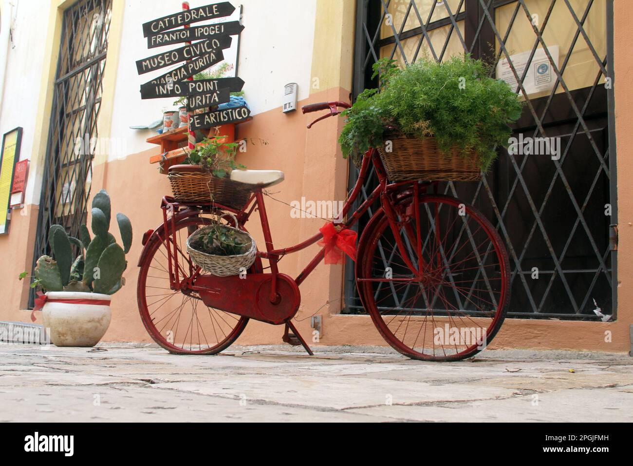 Decorative bicycle in front of the tourist information center, with arrows pointing towards different attractions in Gallipoli, Italy Stock Photo