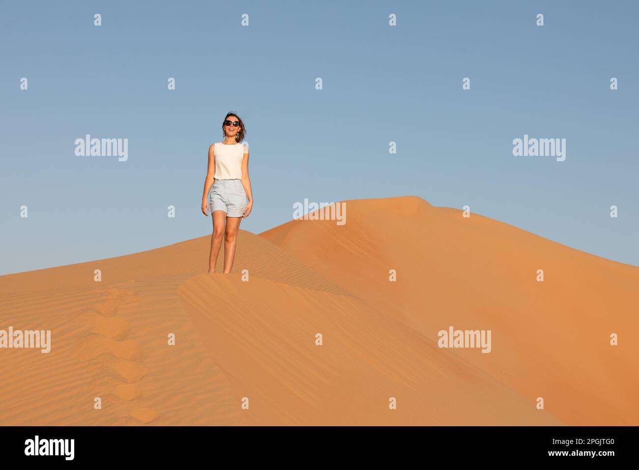 Beautiful young woman posing on the dunes in the desert Stock Photo - Alamy