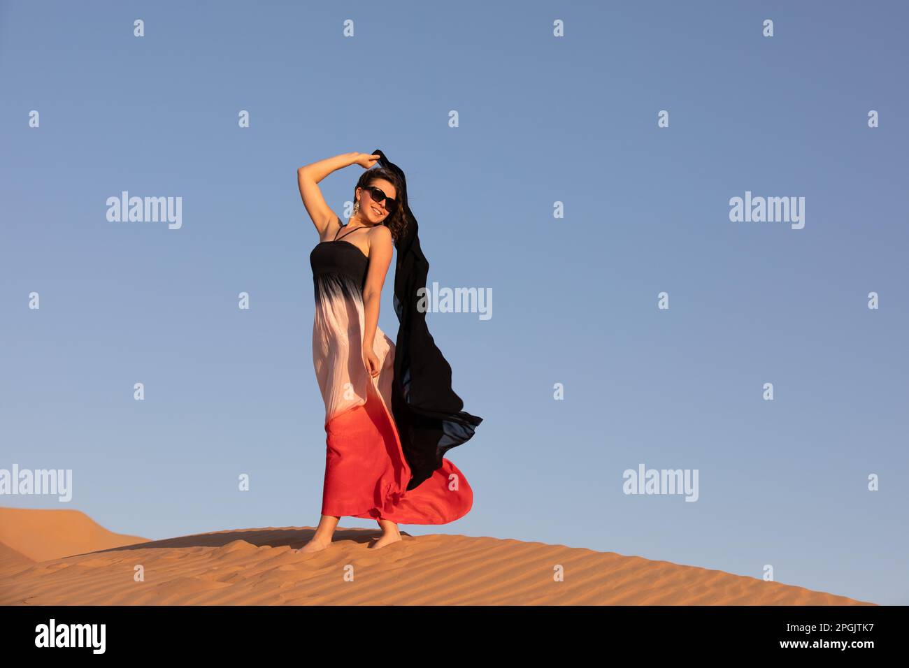 Beautiful young woman posing on the dunes in the desert Stock Photo - Alamy